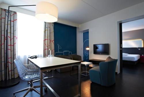 a hotel room with a desk and a bedroom at Postillion Hotel Dordrecht in Dordrecht
