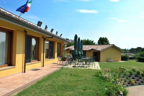 a house with a patio with a table and umbrellas at Le Macerine in Castiglione del Lago