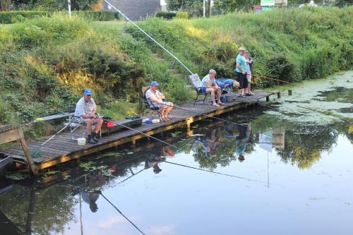 a group of people sitting on a bridge over a river at Luxe Eco Pod op Camping de Stal in Drijber