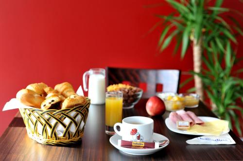 a table with a basket of bread and a cup of orange juice at initial by balladins Roissy / Saint-Mard in Saint-Mard
