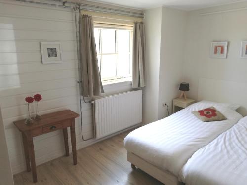 a bedroom with a bed and a window and a table at Sluizeweidje Texel in Den Burg