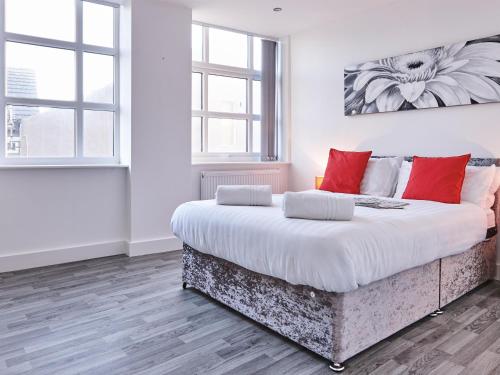 a bedroom with a large bed with red pillows at Fabrik: Winter Gardens Service Apartments 2 in Blackpool