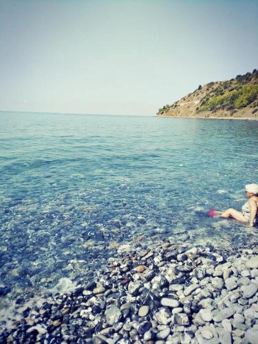 a person sitting on a rocky beach in the water at Villa Calamona in Acciaroli