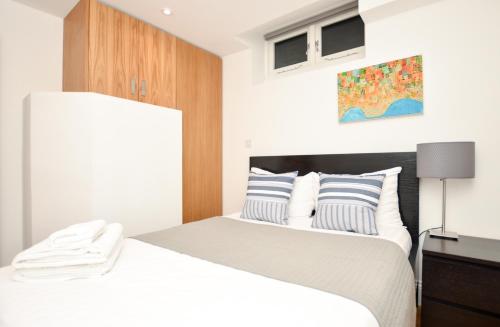 a bedroom with a white bed with a wooden headboard at Kings Cross Serviced Apartments by Concept Apartments in London
