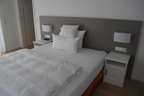 a large bed with white sheets and pillows on it at New Age Boardinghaus P5 in Heilbronn