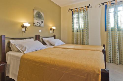 2 letti in una camera da letto con pareti gialle di Alkioni Hotel a Foiníkion