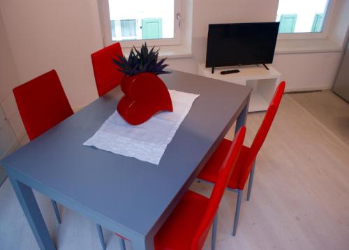 a blue table with red chairs and a television at La Casa di Giò in Arco