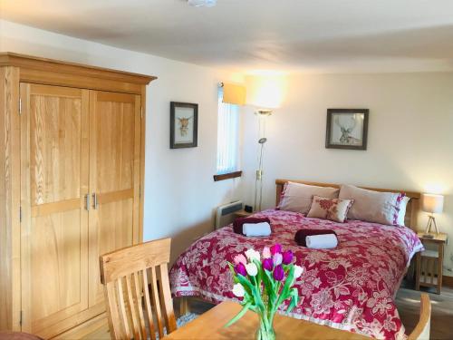 a bedroom with a bed with a vase of flowers on a table at Courtyard Bothy in Grantown on Spey