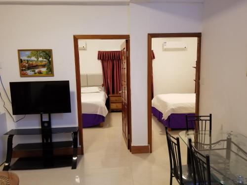 a room with two beds and a tv and a mirror at Enjoy Hotel in Caye Caulker