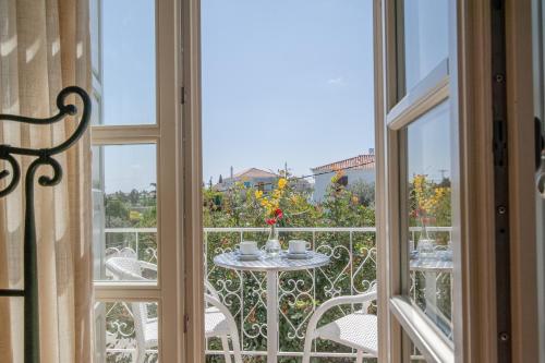 a balcony with a table and chairs and a window at Mimoza in Spetses
