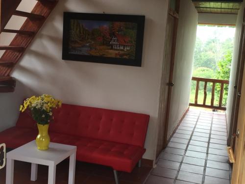 a red couch in a living room with a vase on a table at CABAÑA LOS NOGALES in San Agustín