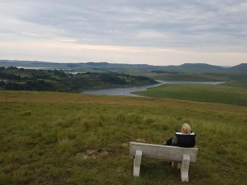 a woman sitting on a bench on a hill overlooking a river at Forty Winks in Nottingham Road