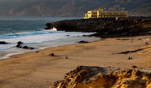 a beach with a building on top of a cliff at Hotel Fortaleza do Guincho Relais & Châteaux in Cascais