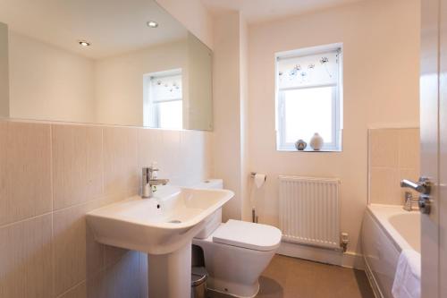 a bathroom with a sink and a toilet and a window at DBS Serviced Apartments - The Terrace in Castle Donington