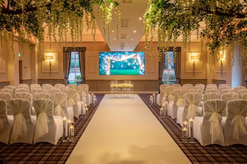 a row of chairs in a banquet hall with a screen at Carden Park Hotel, Golf Resort and Spa in Tilston