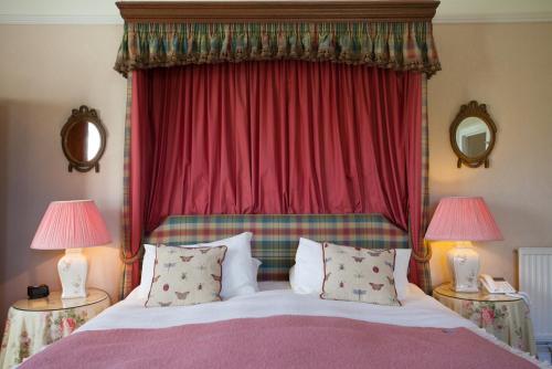a bedroom with a bed with a red curtain and two lamps at Kilcamb Lodge Hotel in Strontian