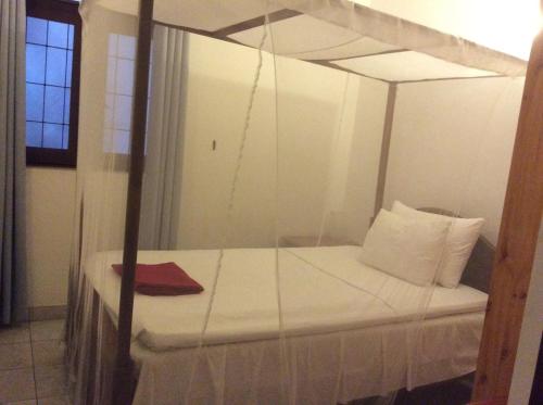 a bedroom with a canopy bed with white sheets and pillows at Angel villa in Negombo