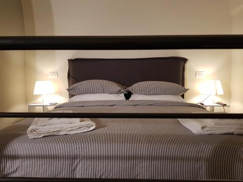 a large bed with a black headboard and two lamps at MammaDada charm rooms in Bari