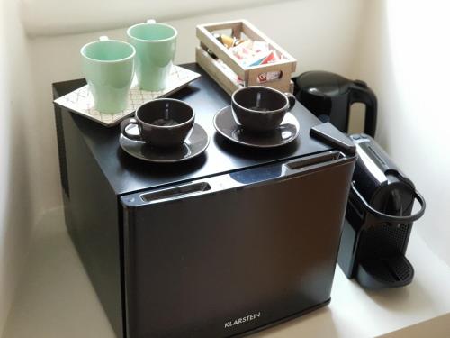 a microwave with cups and saucers on top of it at MammaDada charm rooms in Bari