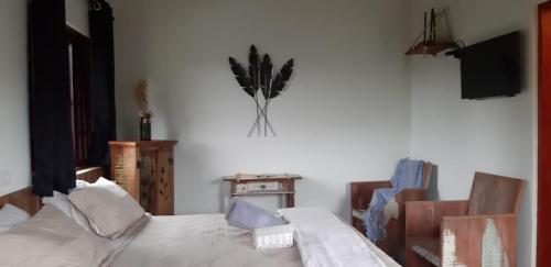 una camera da letto con un letto bianco, una televisione e un fiore sul muro di Chalés e Bangalôs Capim Limão a Bueno Brandão