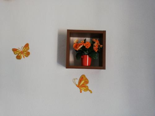 a wall with a picture of a vase of flowers and butterflies at Apartment Pečarević - a holiday with a stunning view in Vis