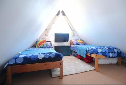 a attic room with two beds and a tv at Clifftop Chalet With Pool in Deal