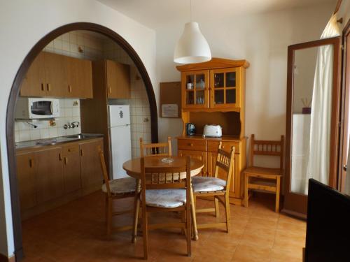 a kitchen and dining room with a table and chairs at Apartamentos Xoroi in Cala en Porter