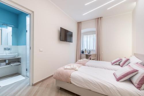 two beds in a room with a bathroom and a sink at Alchimia di Mare in La Spezia