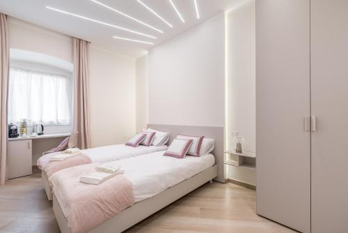 two beds in a white room with pink pillows at Alchimia di Mare in La Spezia