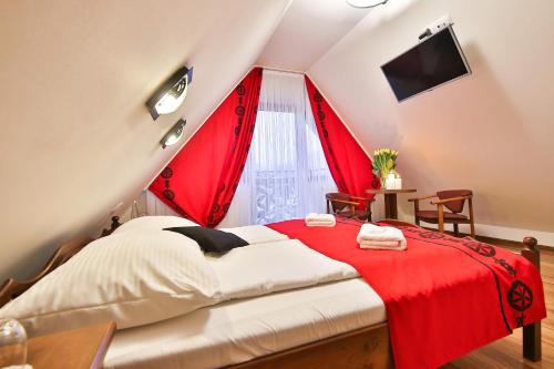 a bedroom with red curtains and a bed in a attic at Grand Podhale Resort&Spa Zakopane - Jacuzzi - Sauna fińska i Łaźnia parowa - Widok na Tatry in Zakopane