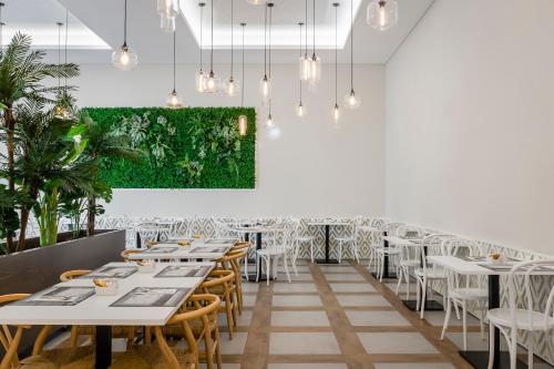 a dining room with tables and chairs and a green wall at EXE Wellington in Figueira da Foz