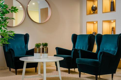 - une salle d'attente avec des chaises bleues, une table et un miroir dans l'établissement EXE Wellington, à Figueira da Foz