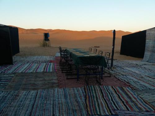 a table and chairs in the middle of the desert at Merzouga Camp and Hostel in Merzouga