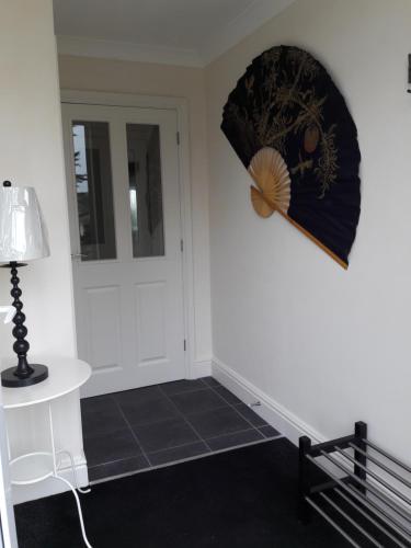 a hallway with a door and a table and a fan at At Cedar Lodge in Ramsey