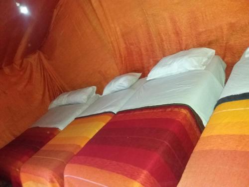 a bedroom with two beds with a rainbow blanket at Merzouga Camp and Hostel in Merzouga