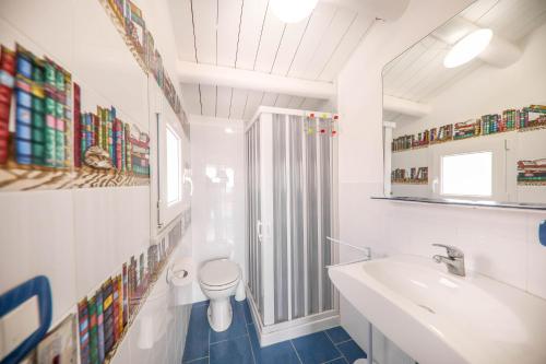 W łazience znajduje się umywalka, toaleta i lustro. w obiekcie Terrazza Azzurra w Cefalù