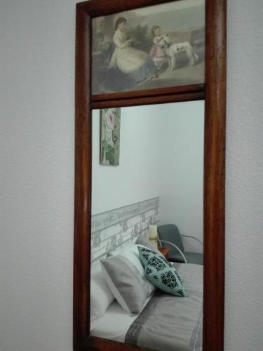 a mirror hanging on a wall next to a bed at La Sabina in Castillejo de Robledo