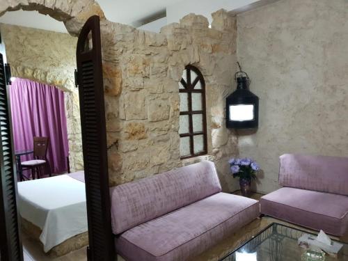 a bedroom with a couch and a bed and a window at Ahiram Hotel Byblos in Jbeil