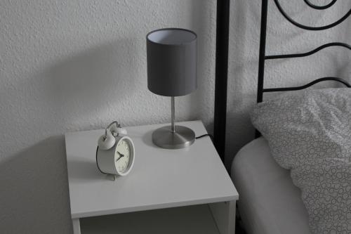a bedside table with a clock and a lamp on it at Schöne 54qm Fewo nahe Rostock und Warnemünde in Lambrechtshagen