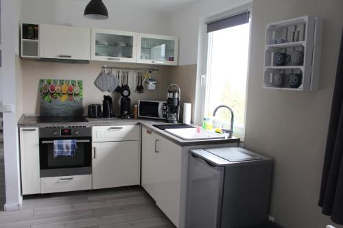 a kitchen with white cabinets and a sink and a window at Schöne 54qm Fewo nahe Rostock und Warnemünde in Lambrechtshagen