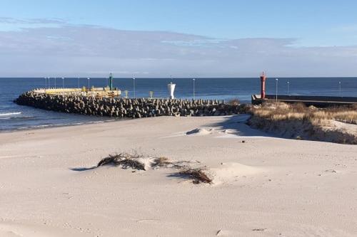 a sandy beach with a pier and the ocean at Casa del Mare, Apartments and more in Łeba