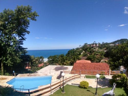 
a beach with a pool and a house at Recanto do Teimoso in Ubatuba
