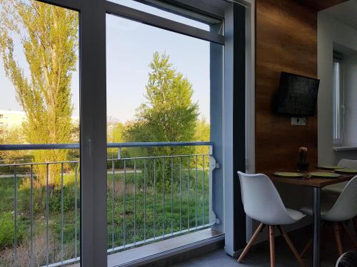 a room with a large window with a table and chairs at Lakefive Apartments Balatonfüred in Balatonfüred