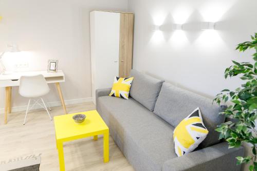 a living room with a gray couch and a yellow table at Apart-Hotel "LAVINA" in Sumy