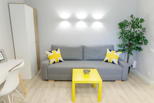 a living room with a gray couch and a yellow table at Apart-Hotel "LAVINA" in Sumy