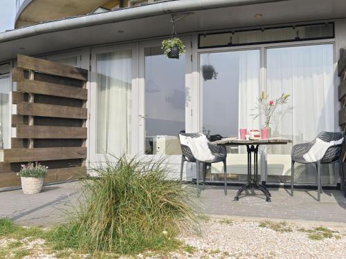 un patio con mesa y sillas. en Modern suites near beach, en Callantsoog