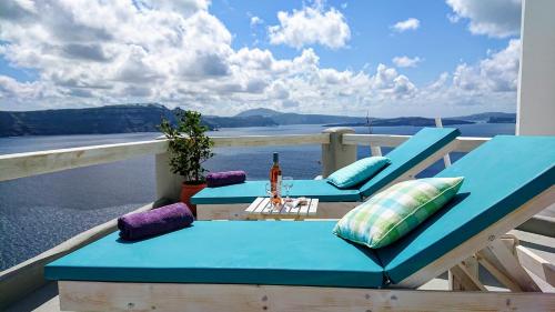 - un balcon avec deux chaises bleues et une table dans l'établissement Aqua & Terra Traditional Cave Houses, à Oia