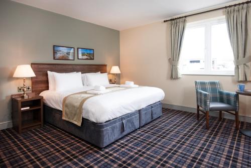 a hotel room with a large bed and a chair at The Amble Inn - The Inn Collection Group in Amble