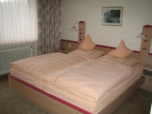 a large bed in a bedroom with two lamps at Landhotel Weinhaus Treis in Weinähr