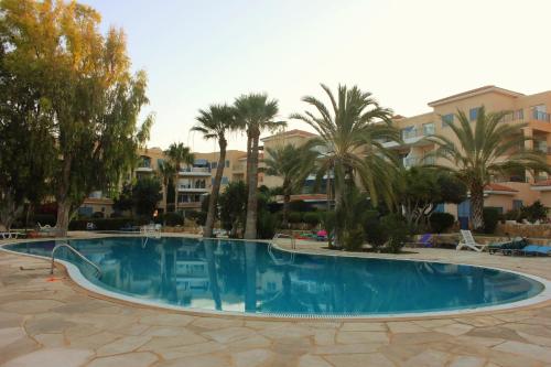 a large swimming pool with palm trees and buildings at Kings Palace Indigo 109 in Paphos